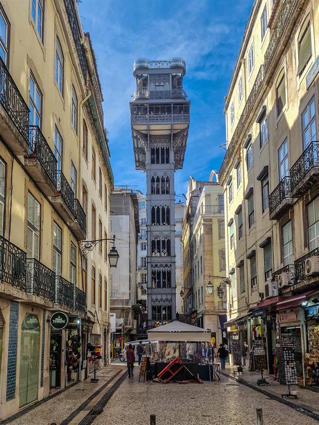 Der Elevador de Santa Justa, auch bekannt als „der Aufzug, der sich in einen Aussichtsturm verirrt hat“, ist eines der kuriosesten Bauwerke Lissabons. Er thront mitten in der Stadt wie ein eiserner Riese, der sich fragt: „Wie bin ich hier eigentlich gelandet? Bin ich ein Aufzug? Ein Turm? Oder einfach nur ein verwirrtes Stück Ingenieurskunst?“ Der Aufzug ist so beliebt, dass sich Touristen gerne stundenlang anstellen, um ihn zu benutzen. Dabei könnte man den Hügel auch einfach hochlaufen – aber wo bliebe da der Charme? Stattdessen drängeln sich die Besucher (inkl. uns) in die enge Kabine, als ginge es um den letzten Platz in einer Rettungskapsel. Oben angekommen, wird man dann mit einem atemberaubenden Blick über Lissabon belohnt.
(01.2024)