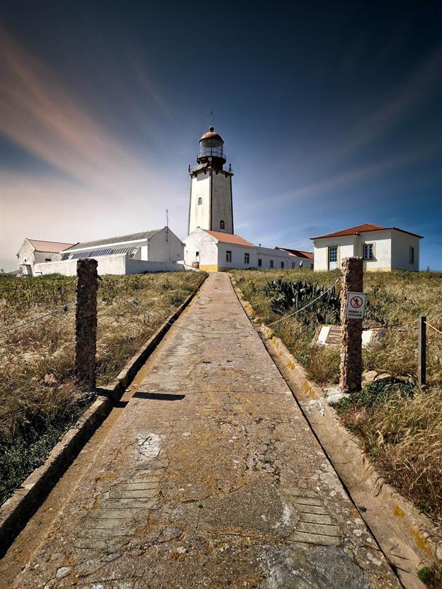 Der Farol da Berlenga ist ein Leuchtturm auf der Ilha da Berlenga Grande, einer kleinen Insel vor der Küste von Peniche in Portugal. Erbaut im Jahr 1841, ist er einer der ältesten Leuchttürme des Landes und dient bis heute als wichtiges Navigationshilfsmittel für Schiffe, die entlang der portugiesischen Atlantikküste unterwegs sind. Der Leuchtturm steht auf einem felsigen Vorgebirge und überragt die Insel mit einer Höhe von 29 Metern. Sein Licht reicht bis zu 50 Kilometer weit und warnt Schiffe vor den gefährlichen Klippen der Berlenga-Inseln. Das Gebäude selbst ist schlicht und funktional gehalten, typisch für die Architektur von Leuchttürmen des 19. Jahrhunderts.
(05.2024)